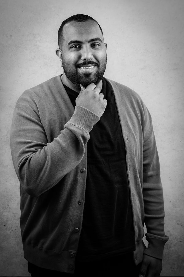 Mazin Housin, smiling, in a black and white portrait